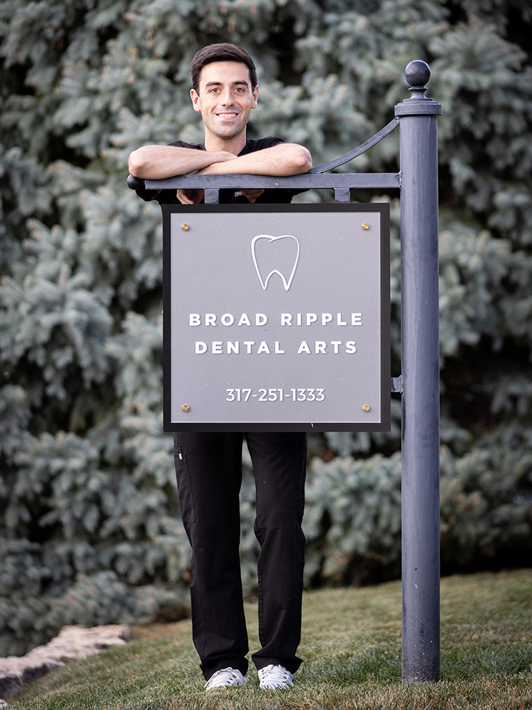 Doctor Corrado in front of the Broad Ripple Dental Arts Sign